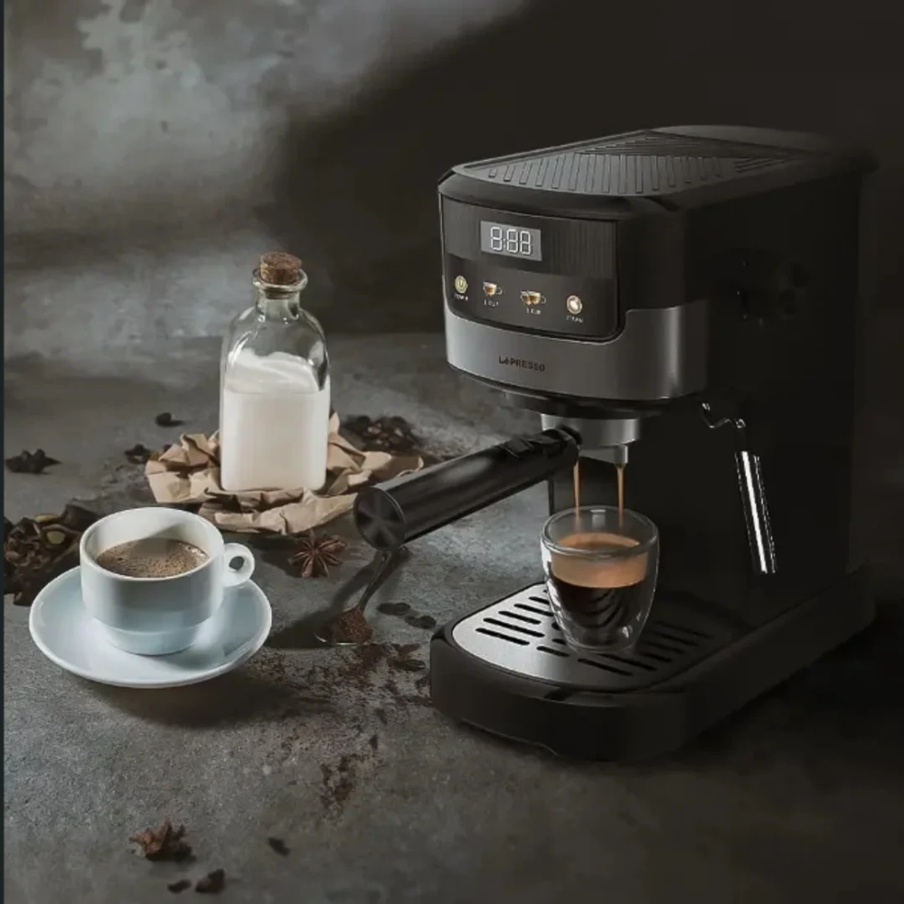 Coffee machine dispensing coffee into a glass on a rustic surface with a bottle of milk and a cup of coffee.