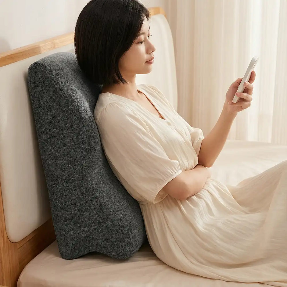 Woman using Green Lion Relief Wedge Pillow for comfortable back support while reading in bed